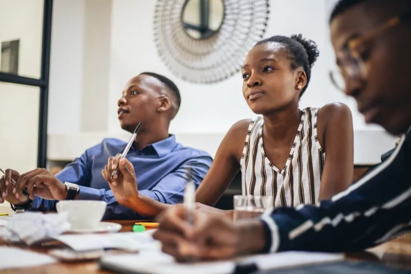 A small group listening and taking notes around a table in a workshop session
