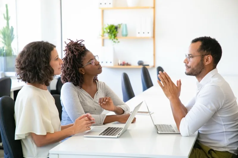 An advisor talking through an idea with two founders across a meeting table