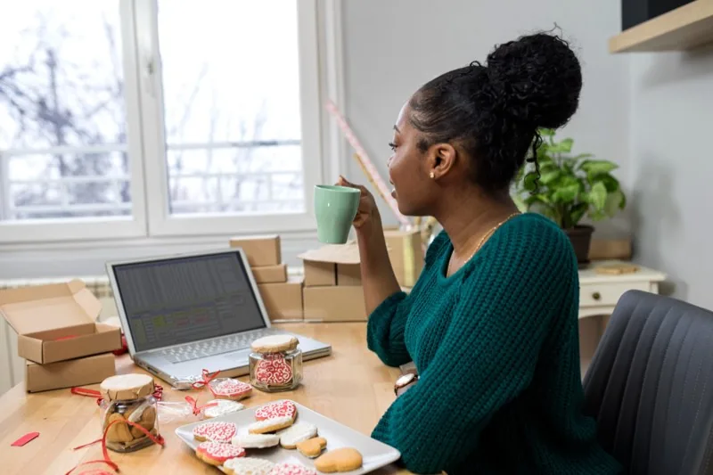 A founder reviewing a spreadsheet on her laptop in her home production kitchen